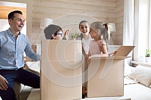 Family with children excited moving new house playing unpacking boxes
