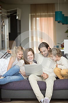 Family with children having fun using laptop on sofa, vertical