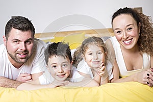 Family, children and home concept - happy family with two kids under blanket at home