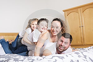 Family, children and home concept - happy family with two kids under blanket at home