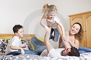 Family, children and home concept - happy family with two kids under blanket at home