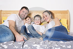 Family, children and home concept - happy family with two kids under blanket at home