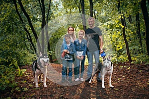 Family with children, and husky dogs in the forest