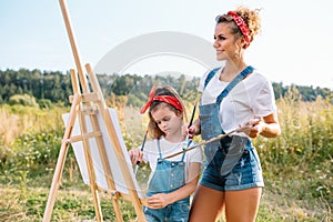 family, children and people concept - happy mother and daughter drawing and talking over green background. Mother& x27;s