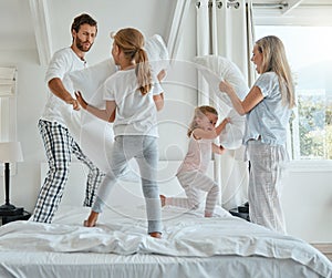 Family, children and pillow fight with parents and girl siblings having fun playing in a bedroom together. Kids, happy