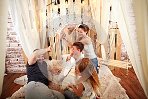 Family with children playing with pillows at home on bed