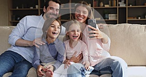 Family with children sit on sofa having fun using cellphone