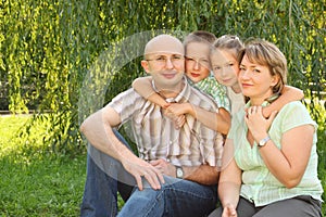 Family with children sitting at grass near osier