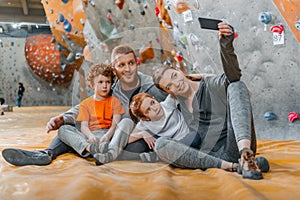 Family with children taking a selfie with smartphonesitting on a mat at gym