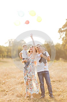 Family with children walking outdoors in summer field at sunset. Father, mother and two children sons having fun in