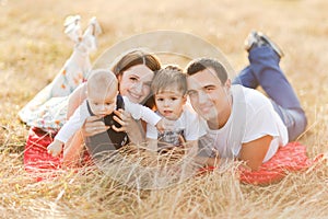 Family with children walking outdoors in summer field at sunset. Father, mother and two children sons having fun in