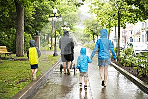 Family with childs walk on rainy day with raincoat