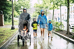 Family with childs walk on rainy day with raincoat