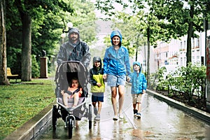 Family with childs walk on rainy day with raincoat