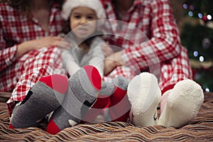 Family in Christmas Cocks. Happy Family Sitting On Bed. Mother, Father And Child Having Fun In Christmas Time. Man, Woman And Kid