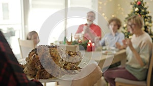 Family Christmas dinner. Hostess serves a baked goose.