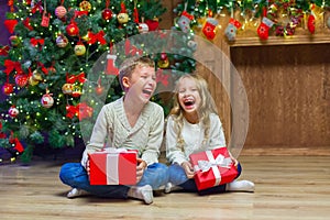 Family on Christmas eve at fireplace. Kids opening Xmas presents