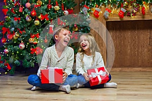 Family on Christmas eve at fireplace. Kids opening Xmas presents