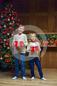 Family on Christmas eve at fireplace. Kids opening Xmas presents