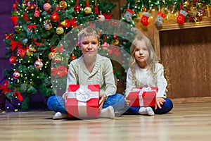 Family on Christmas eve at fireplace. Kids opening Xmas presents