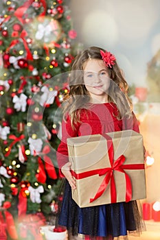 Family on Christmas eve at fireplace. Kids opening Xmas presents. Children under Christmas tree with gift boxes. Decorated living