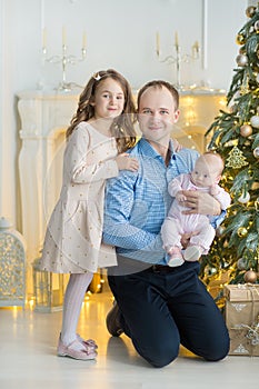 Family on Christmas eve at fireplace. Kids opening Xmas presents. Children under Christmas tree with gift boxes. Decorated living