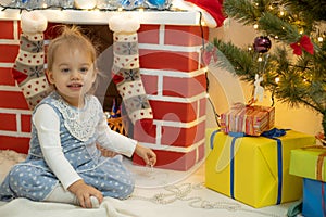 Family on Christmas eve at fireplace. Mother and little kids opening Xmas presents. Children with gift boxes. Living