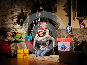 Family on Christmas eve. Mother and daughter with Xmas presents. Family with gift boxes. Living room with decorated tree. Cozy