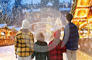 Family at Christmas fair in snow. Xmas market