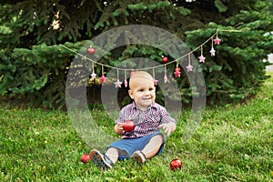 Family Christmas in July. Portrait of little boy near christmas tree. Baby decorating pine. Winter holidays and people concept.