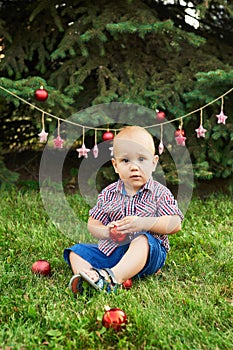 Family Christmas in July. Portrait of little boy near christmas tree. Baby decorating pine. Winter holidays and people concept.