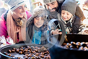 Family on Christmas market eating sweet roasted chestnuts