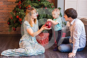 Family, christmas, x-mas, winter, happiness and people concept - smiling family with baby boy sitting under xmas tree