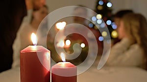 Family Christmas Meal. A young man lights the candles at the Christmas table. Big family and Christmas tree in