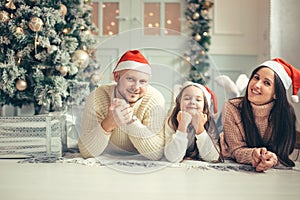 Family in Christmas Santa hats lying on bed. Mother father and baby having fun