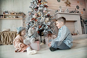 Family on Christmas With a teddy bear under the Christmas tree. Kids opening Xmas presents with gift boxes. Bright living room