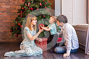 Family, christmas, x-mas, winter, happiness and people concept - smiling family with baby boy sitting under xmas tree