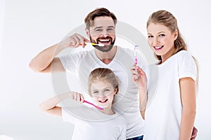 Family cleaning teeth with toothbrushes together on white