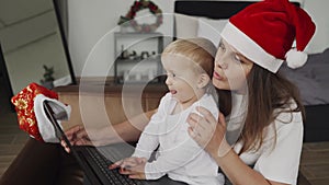 family communicates online with their relatives. Mom and her son near the laptop at Christmas. Child and mother in