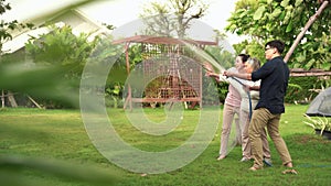 Family Concept, Asian couple on vacation evening watering the plants with their mother in the garden outside with happy smiles