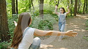 Family concept. Cute baby girl runs to Mom`s embrace in the park