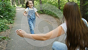 Family concept. Cute baby girl runs to Mom`s embrace in the park