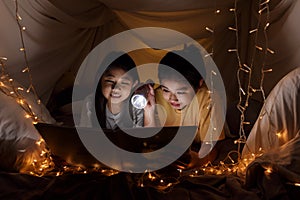 Family concept. elder sister and sister reading book with flashlight together before bedtime. Sister read story book together in