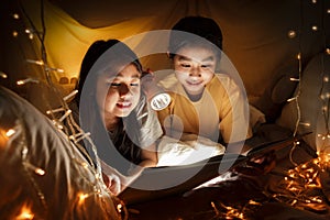 Family concept. elder sister and sister reading book with flashlight together before bedtime. Sister read story book together in