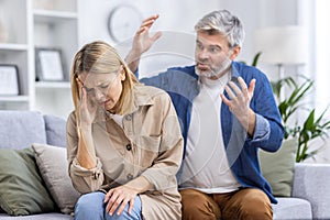 Family conflict quarrel, man shouting and upset woman close-up, couple sitting on sofa in living room