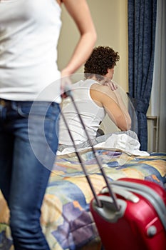 Family conflict. Young woman with a suitcase leaves from the husband. Family conflict. Divorce. Selective focus on man