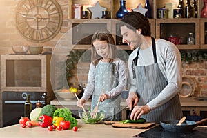 Family Cooking. Father Teaching His Little Daughter How To Cook Vegetable Salad