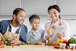 Family cooking and looking at a tablet together