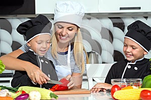 A family of cooks.Healthy eating. Happy family mother and children prepares vegetable salad in kitchen