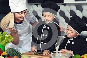 A family of cooks.Healthy eating. Happy family mother and children prepares vegetable salad in kitchen